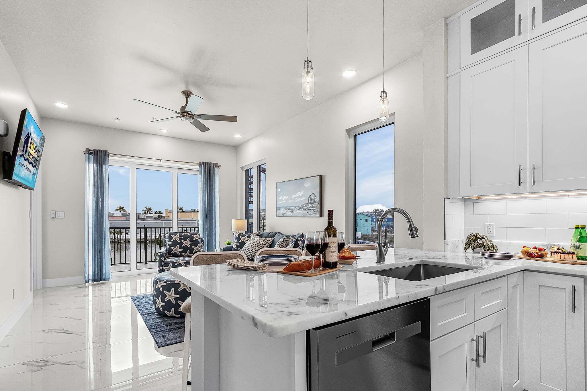 A modern kitchen with a large island, a dining area with a sofa, and a balcony with a view.
