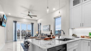 Une cuisine moderne dotée d’un grand îlot central, d’un coin repas avec un canapé et d’un balcon offrant une vue agréable.