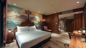 Ein geräumiges Schlafzimmer mit einem großen Bett, einem Holztisch, einem Stuhl, einem kleinen Tisch und einer Wandmalerei.