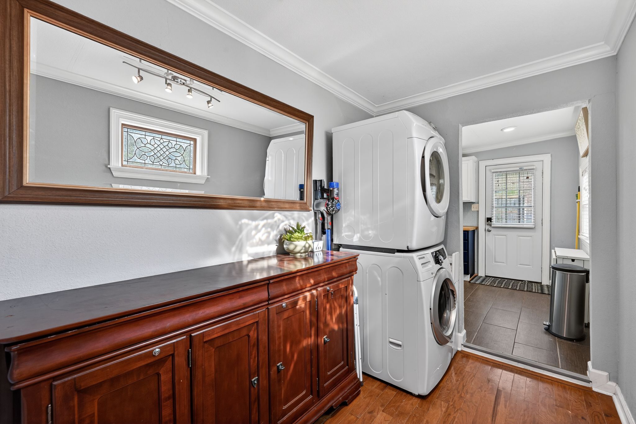 A laundry room with a washing machine, dryer, and a wooden cabinet.