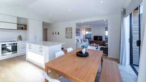 Una cocina moderna con armarios blancos, una mesa de comedor de madera y un horno empotrado.