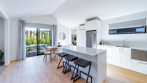 Una cocina moderna con una isla central, taburetes de bar y un comedor con vistas.