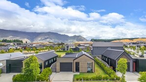 Una zona residencial con casas modernas, cielo despejado y montañas al fondo.