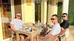Ruokailutila, jossa on rottinkihuonekaluja, lasipöytä ja näkymä ulos.