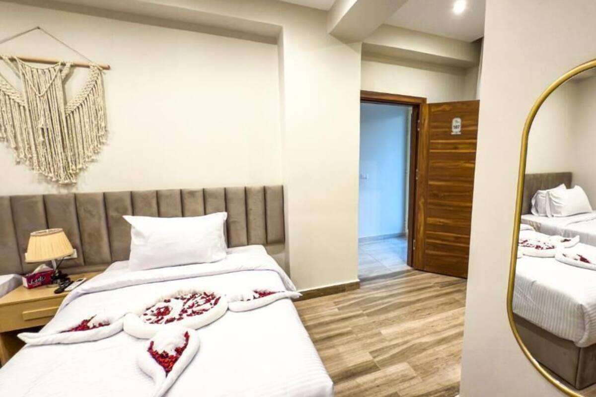 A hotel room with a bed, bedside table, and a mirror.