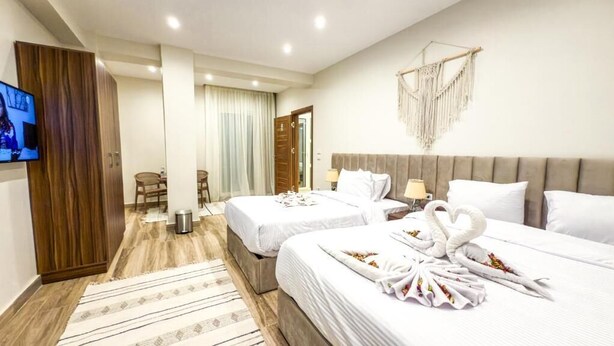 Hotellihuone, jossa on kaksi sänkyä, televisio, työpöytä ja oleskelualue.