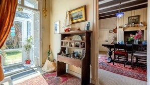 Ein Zimmer mit einem Holzboden, einer Tür, die nach draußen führt, einem Essbereich mit Tisch und Stühlen sowie einem Kamin.