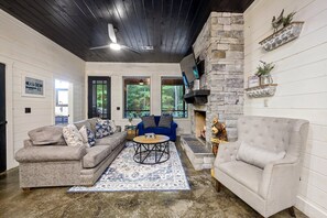 Ein Wohnzimmer mit Kamin, Steinwand, blauem Sofa und grauem Sofa.