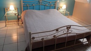 Une chambre à coucher avec un lit en métal, deux tables de chevet avec des lampes et un mur bleu.