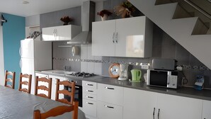Une cuisine moderne avec des meubles blancs, une cuisinière à gaz, un four à micro-ondes et une machine à café.