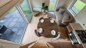 A spacious living area with a round wooden table set for four, a sofa, and a kitchen area with a stove. - Lovely home in Oud Gastel with WiFi (Oud Gastel)