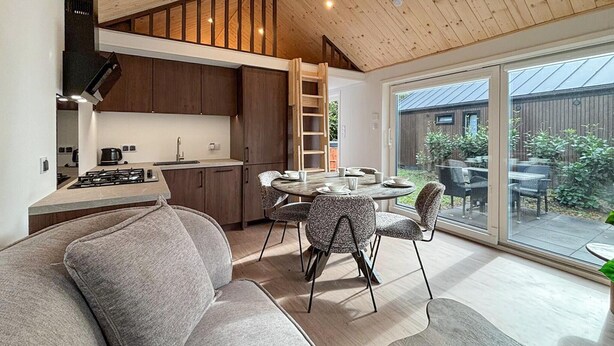 Eine moderne Küche mit Holzausstattung, einem eingebauten Herd und einem Essbereich mit rundem Tisch und Stühlen.
