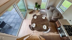 Ein geräumiger Wohnbereich mit einem runden Holztisch, gedeckt für vier Personen, einer Couch und einer Küchenzeile mit Herd.