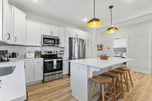 A modern kitchen with white cabinetry, stainless steel appliances, a central island with bar stools, and pendant lighting. - View of Outdoor Pool&Table Rock_Arcades_Pvt Hot Tub_Shuffleboard_Free Tickets (Kimberling City)