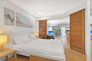 A hotel room with a bed, a TV, a desk, and a balcony with a view. - Comfy 1BR + Free Parking |  Stroll to Parklands (Southport)