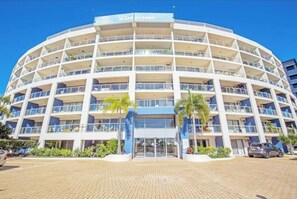 A multi-story hotel with a circular facade, balconies, and a sign reading 'The Bays Resort'. - Comfy 1BR + Free Parking |  Stroll to Parklands (Southport)
