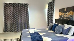 Quarto com cama, cortinas, ventilador de teto, ar condicionado e um quadro na parede.