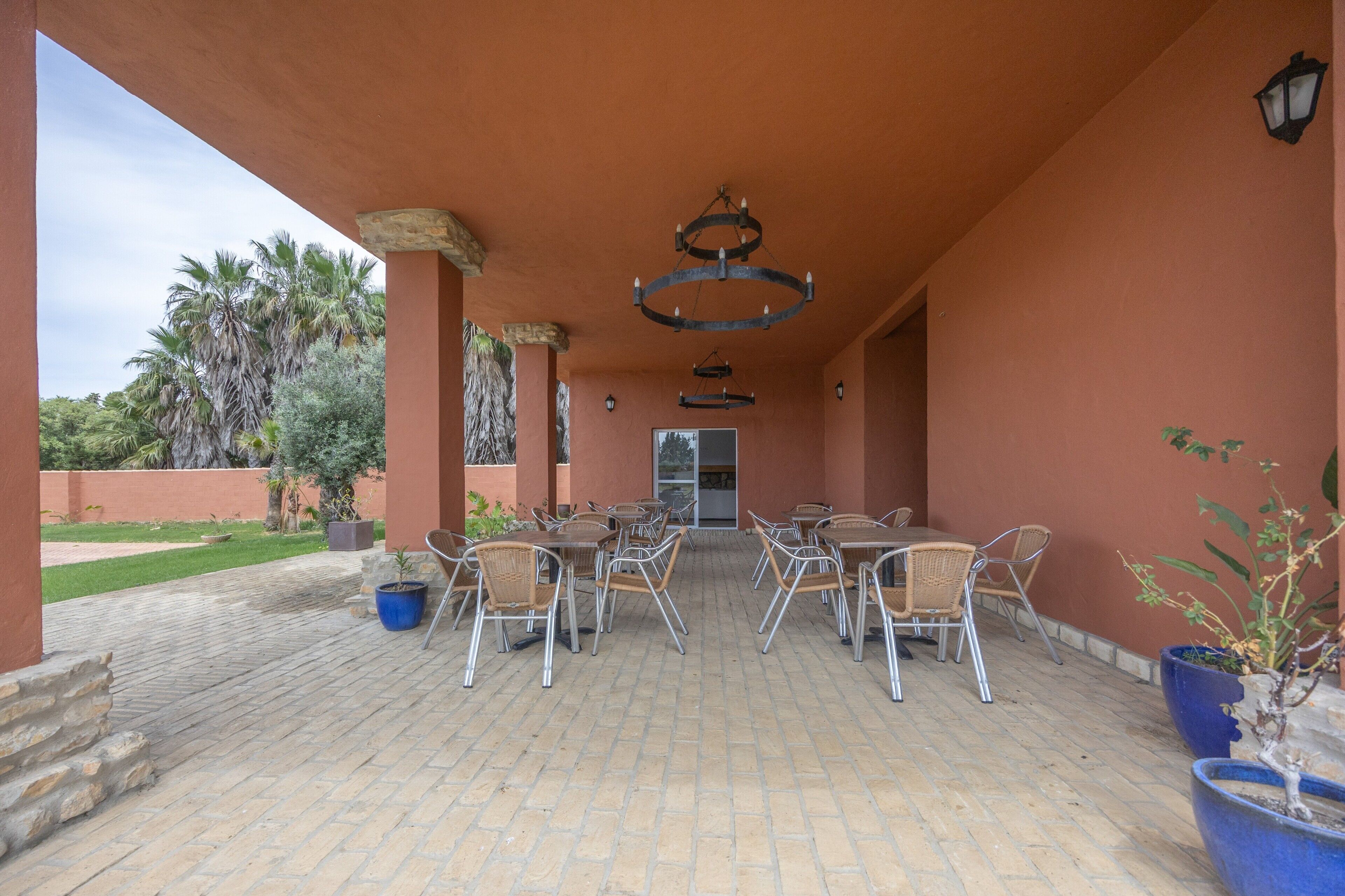 An outdoor patio with brick flooring, metal chairs, and tables arranged for dining.