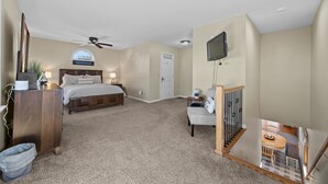 Una camera da letto con un letto, una scrivania, una sedia, una televisione e un ventilatore a soffitto.