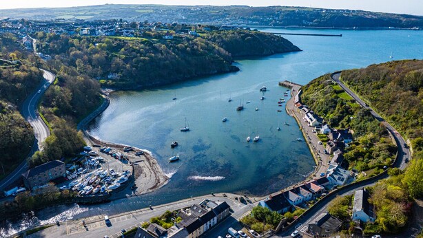 An aerial view of a coastal town with a marina, roads, and residential areas.