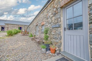 A stone building with a sign reading 'Old Spot Cottage,' a gravel driveway, and outdoor seating. - Old Spot Cottage, Holiday Cottage Strumble Head Peninsula, Sleeps 6, 3 bedrooms,  bathrooms (Goodwick)