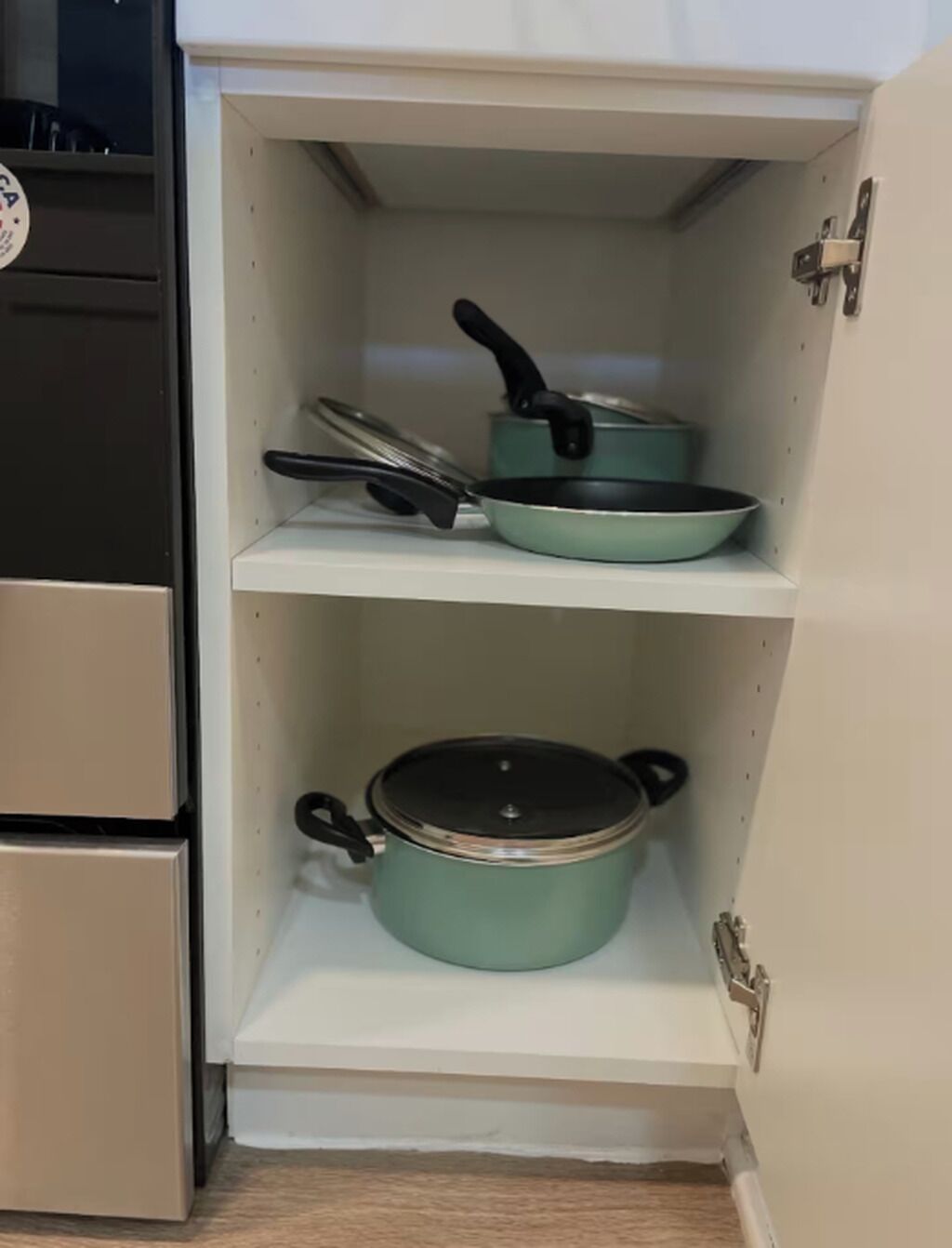 Una cocina con dos estantes, cada uno con una olla y una sartén.