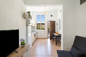 A compact living space with a TV, kitchenette, dining area, and a view of the outdoors. - Vacation Home 'Casa 4' with Mountain View, Wi-Fi and Air Conditioning (Taidía)