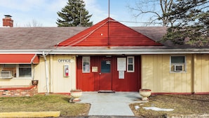 A building with a red roof, a yellow facade, and a sign indicating 'OFFICE' on the front. - Budget INN (Flint)