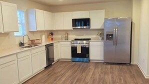Una cocina moderna con armarios blancos, electrodomésticos de acero inoxidable y piso de madera.