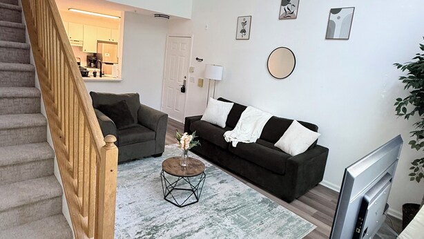 Ein Wohnzimmer mit Treppe, Sofa, Couchtisch und Fernseher.
