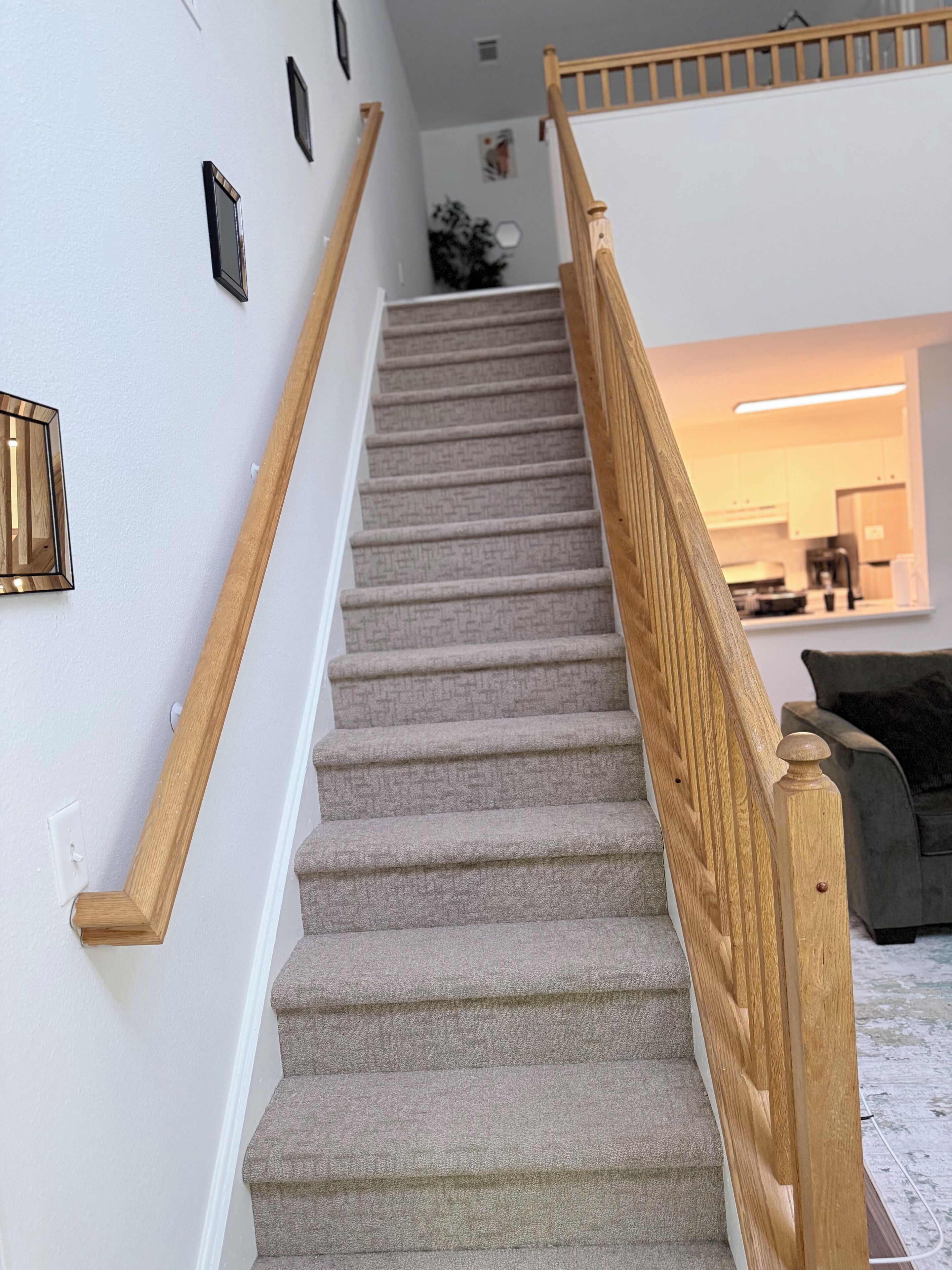 A carpeted staircase with wooden railings leading to a living area with a sofa and a coffee machine.