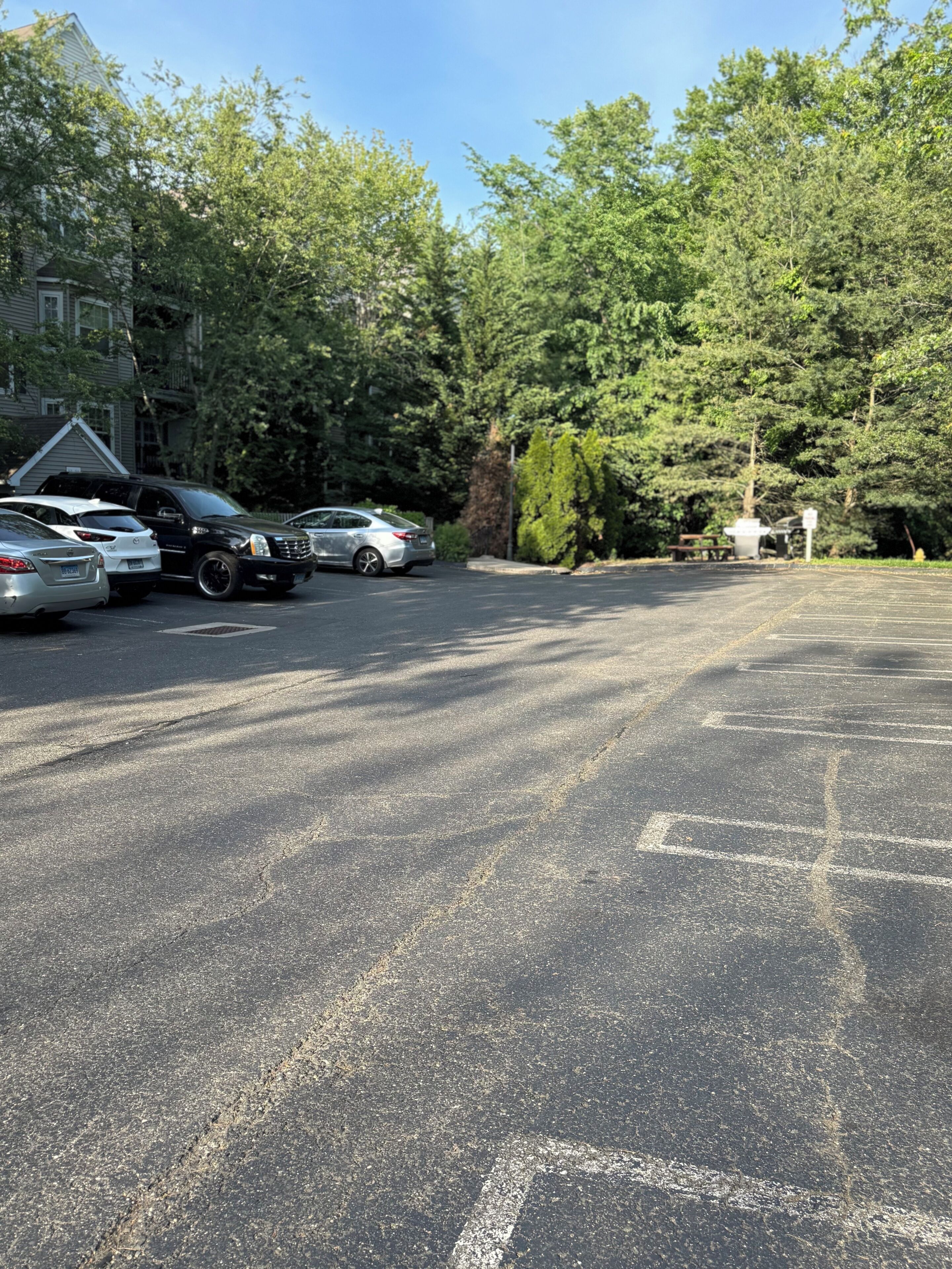A parking lot with several cars, trees, and a building in the background.