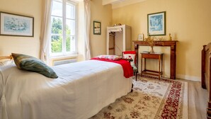 Un dormitorio con cama, una silla, una mesa y un ventanal.