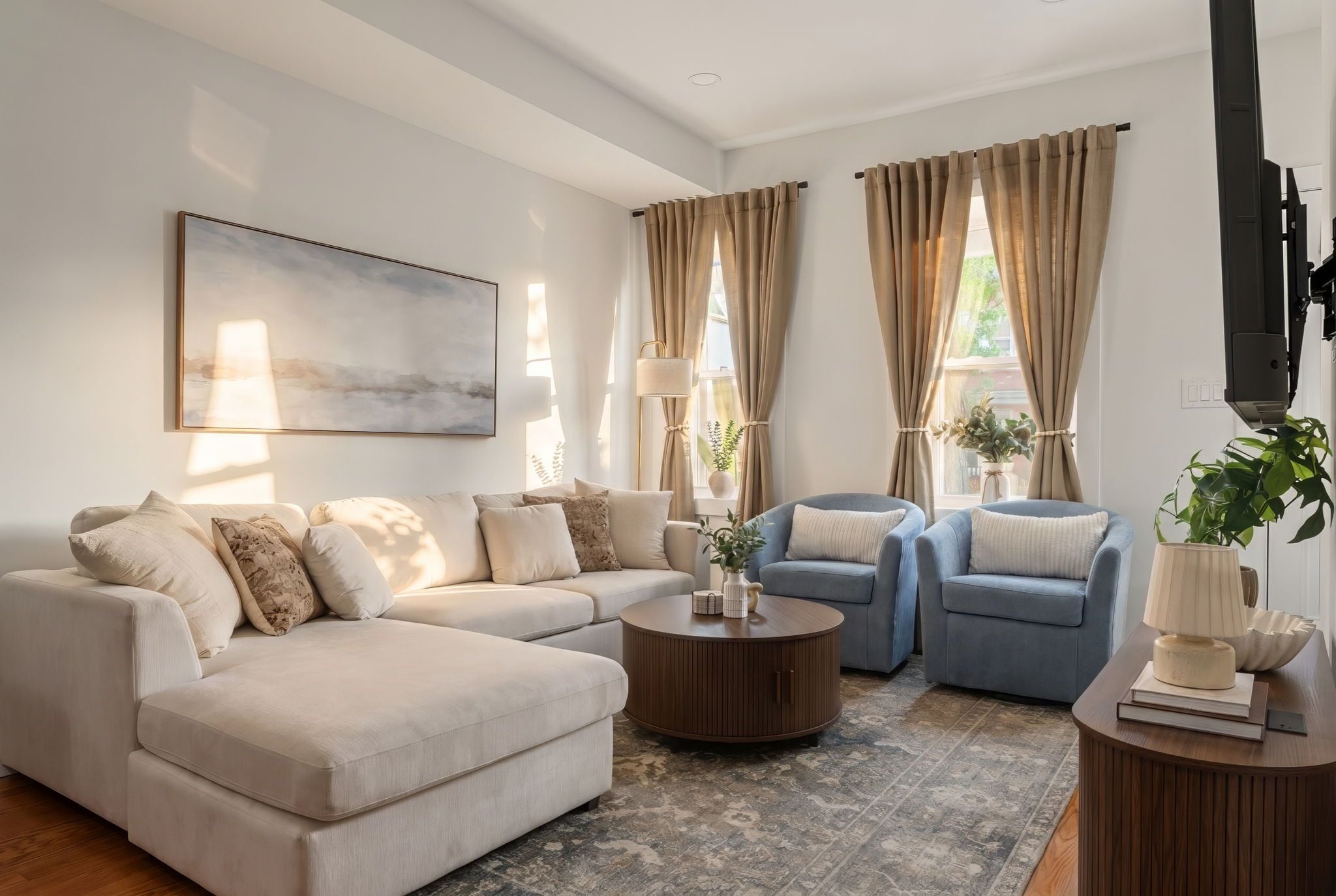 A living room with a sectional sofa, two armchairs, a coffee table, and a TV.