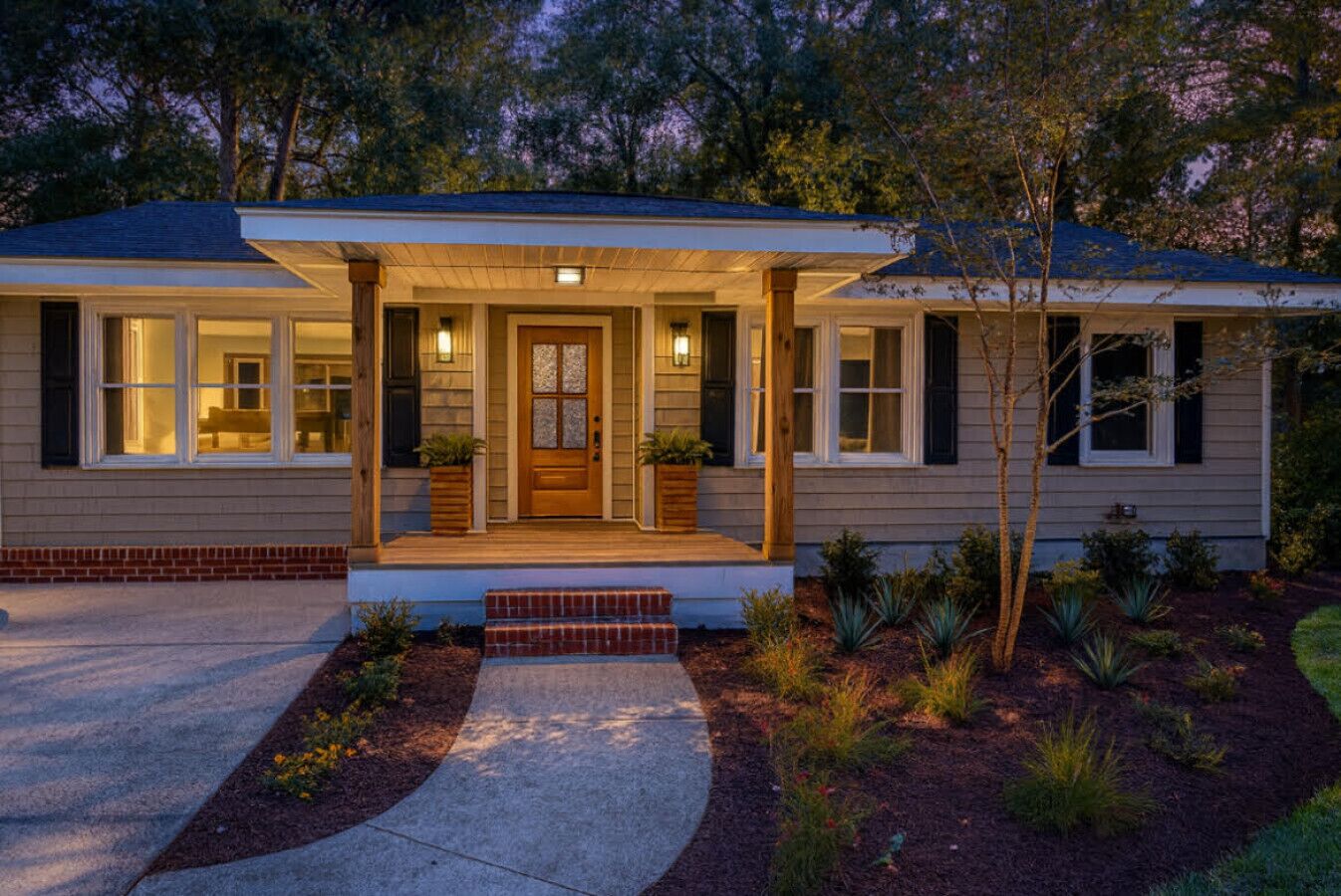 Ein eingeschossiges Haus mit Veranda, Garage und einem angelegten Vorgarten.