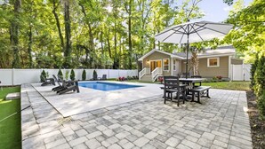 Ein Garten mit Schwimmbad, Gartenmöbeln und einem Haus.