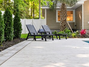 Eine Beton-Terrasse mit zwei Liegestühlen und einem kleinen Pool.