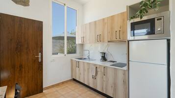 Una cocina con armarios de madera, microondas, fregadero y refrigerador.