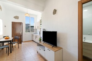 Une cuisine compacte équipée d’un téléviseur, d’une table à manger, de chaises et d’une fenêtre donnant sur un paysage montagneux.