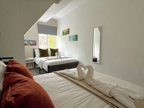 Ein Hotelzimmer mit Bett, Schreibtisch, Stuhl, Fenster und Spiegel.