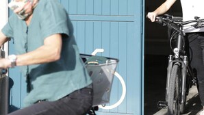 En person på cykel med kurv, en bygningindgang og en dør.