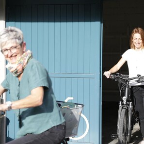 A person on a bicycle with a basket, a building entrance, and a door.