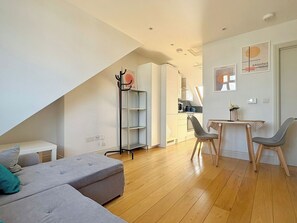 Eine moderne Wohnung mit Schlafzimmer im Loft-Stil, einem Essbereich und einem Wohnzimmer mit Sofa und Couchtisch.