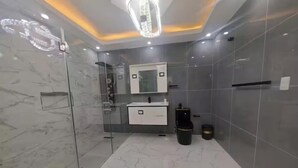 Ein modernes Badezimmer mit Duschkabine aus Glas, einem weißen Waschtisch und einem Spiegel über dem Waschbecken.