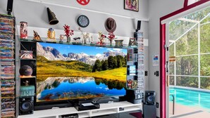 Olohuoneessa on suuri taulutelevisio, DVD-levyillä täytetty kirjahylly, kaiutin ja ikkuna, josta avautuu näkymä järvelle ja vuorille.