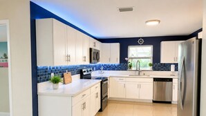 A modern kitchen with white cabinets, a stainless steel refrigerator, and a blue-tiled backsplash. - 3 bedroom, 2 full baths, with private pool, barbecue and  pet designated a (Oakland Park)