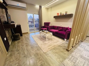Ein Wohnzimmer mit einem violetten Sofa, einem weißen Couchtisch und Blick durch eine Glastür.