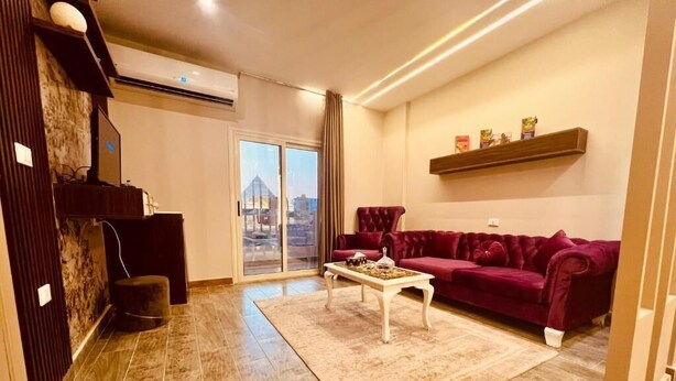 A living room with a red sofa, a white coffee table, and a city view through a large window. - pyramids Moon IIn (Giza)