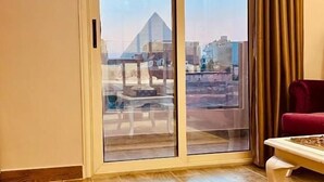 A room with a sliding glass door leading to an outdoor area, a wooden floor, and a red chair. - pyramids Moon IIn (Giza)