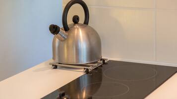 Uma chaleira de aço inoxidável sobre um fogão por indução preto.